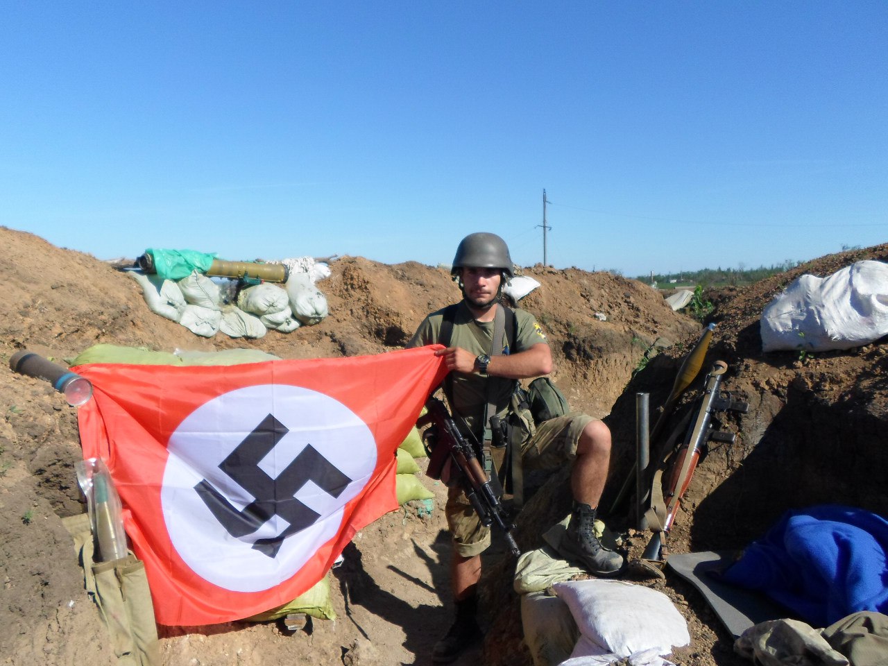 Ukrainian soldier with Azov patch proudly showing Nazi banner